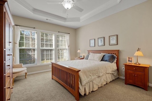 bedroom with baseboards, visible vents, a tray ceiling, light carpet, and crown molding