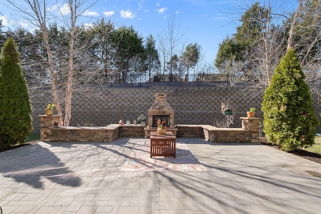 view of patio with an outdoor stone fireplace and fence