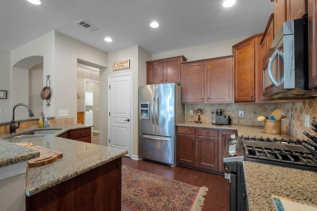 kitchen with light stone countertops, visible vents, a sink, dark wood-type flooring, and appliances with stainless steel finishes