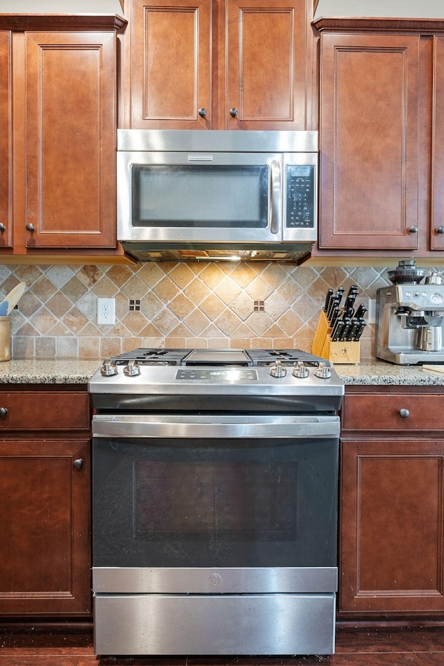 kitchen featuring decorative backsplash, light stone counters, brown cabinets, and stainless steel appliances