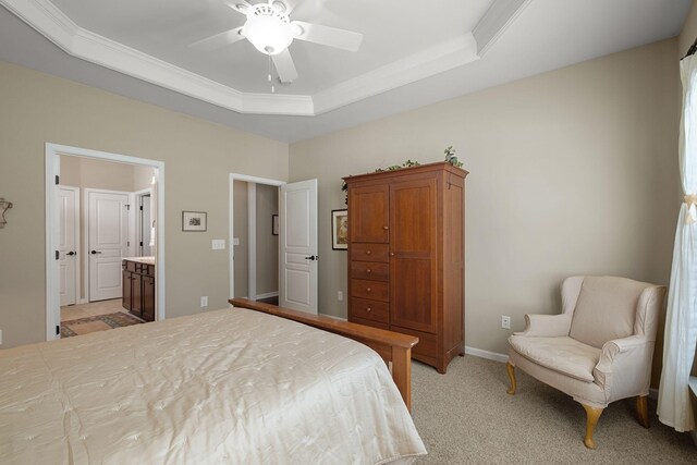 bedroom with baseboards, crown molding, ensuite bathroom, light carpet, and a raised ceiling