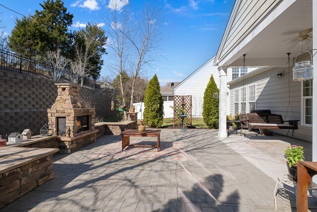 view of patio / terrace featuring an outdoor stone fireplace and fence