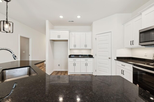 kitchen with visible vents, a sink, white cabinetry, decorative light fixtures, and black electric range oven