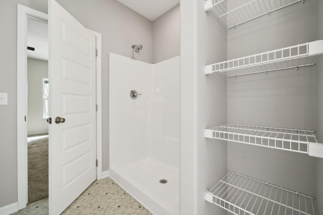 bathroom featuring a walk in shower and baseboards