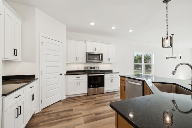 kitchen featuring recessed lighting, appliances with stainless steel finishes, wood finished floors, white cabinetry, and a sink