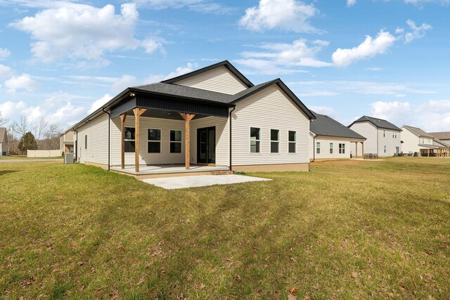 back of house featuring a yard, a patio area, and a shingled roof