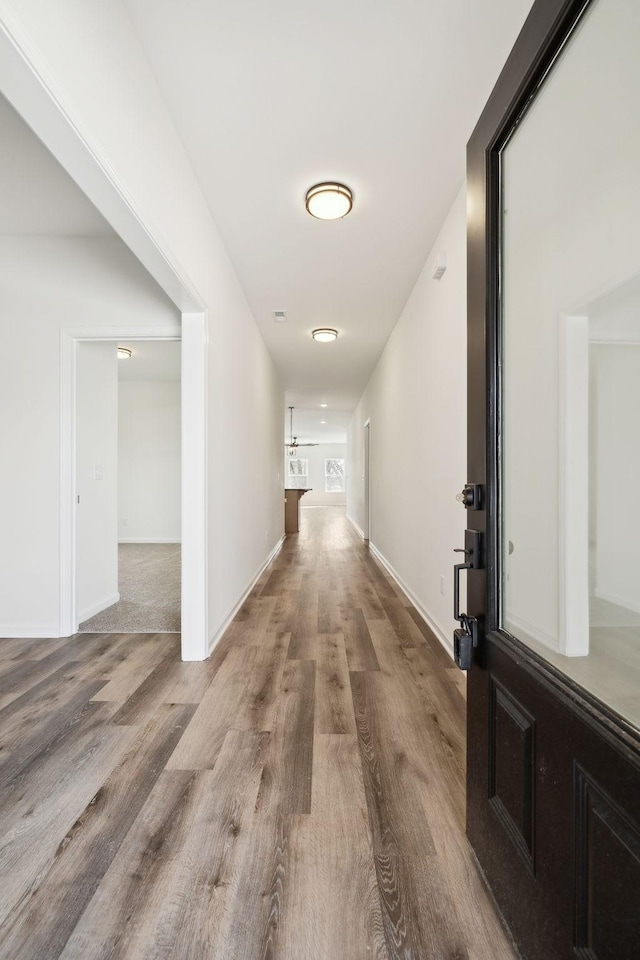 hall with baseboards and wood finished floors