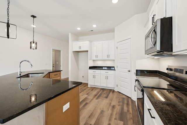 kitchen with light wood finished floors, decorative light fixtures, recessed lighting, stainless steel appliances, and a sink