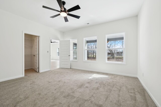 unfurnished bedroom with visible vents, baseboards, carpet floors, ceiling fan, and a walk in closet