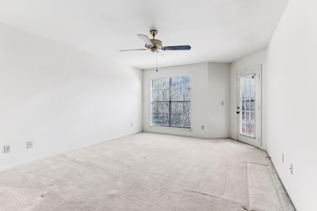 carpeted empty room featuring ceiling fan and baseboards