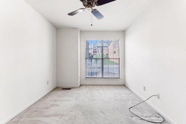 carpeted empty room with visible vents, a ceiling fan, and baseboards