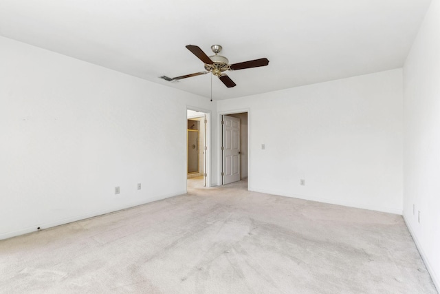 spare room featuring a ceiling fan, baseboards, visible vents, and light carpet