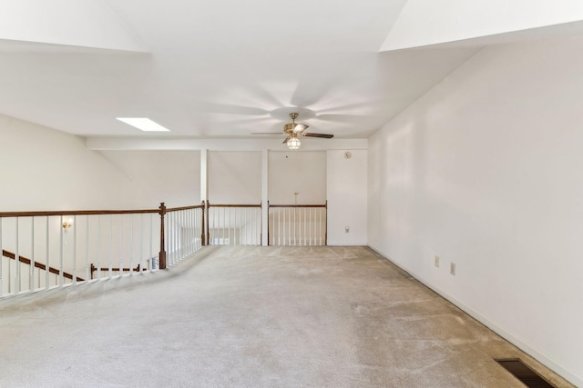 unfurnished room featuring a skylight, carpet flooring, a ceiling fan, and visible vents