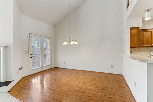 entrance foyer featuring baseboards, visible vents, high vaulted ceiling, an inviting chandelier, and light wood-type flooring