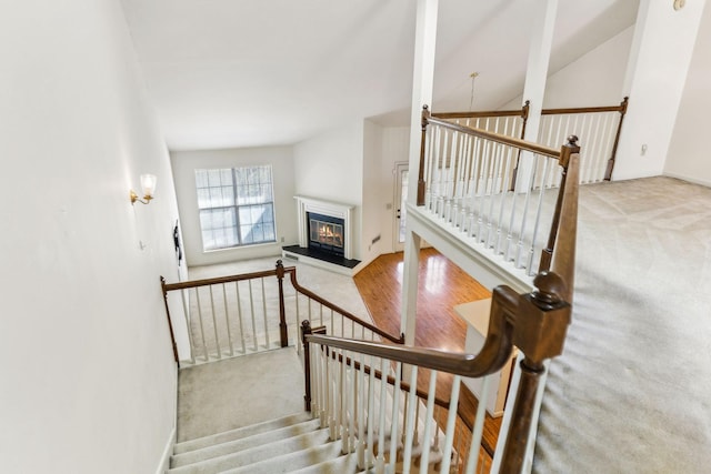 staircase featuring a glass covered fireplace and carpet