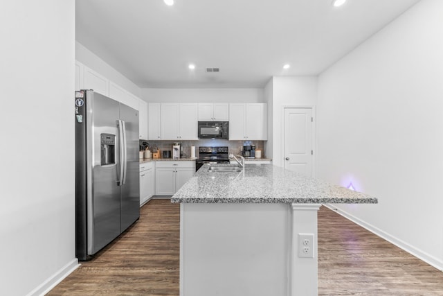 kitchen featuring dark wood finished floors, electric range, decorative backsplash, black microwave, and stainless steel fridge