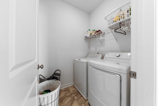 clothes washing area with baseboards, washing machine and dryer, and laundry area