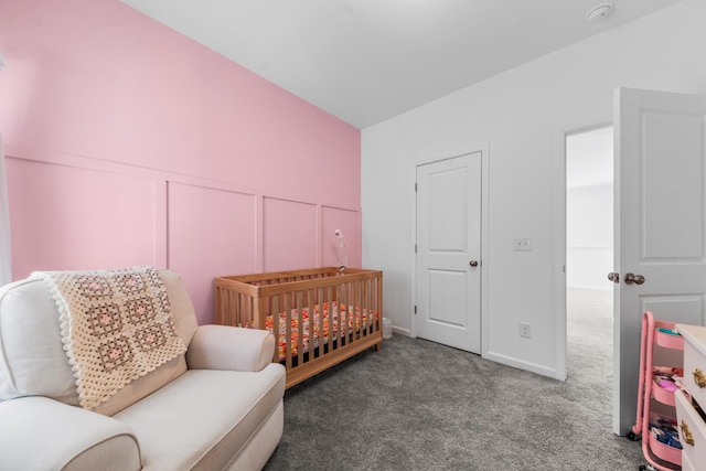 bedroom with a decorative wall, wainscoting, a crib, and carpet floors