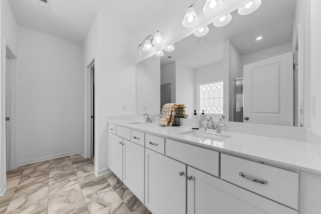 bathroom with double vanity, marble finish floor, baseboards, and a sink