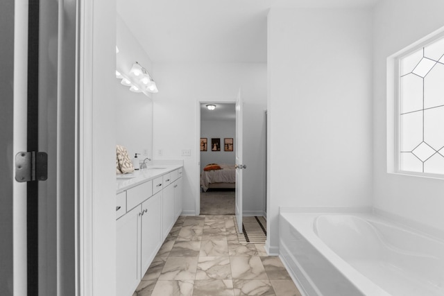 bathroom with a garden tub, double vanity, marble finish floor, ensuite bath, and a sink