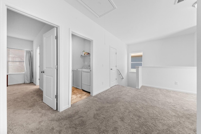 carpeted spare room featuring attic access, washing machine and dryer, baseboards, and visible vents