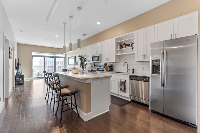 kitchen featuring a sink, a center island, appliances with stainless steel finishes, white cabinets, and open shelves