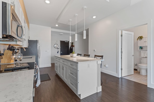 kitchen featuring decorative light fixtures, recessed lighting, appliances with stainless steel finishes, light stone countertops, and dark wood-style flooring