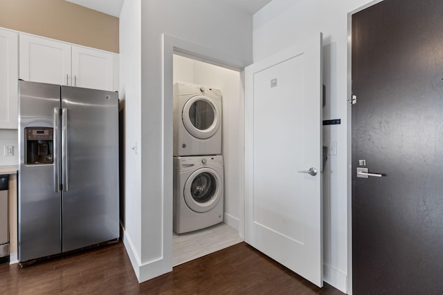 clothes washing area featuring dark wood finished floors, laundry area, and stacked washer / drying machine