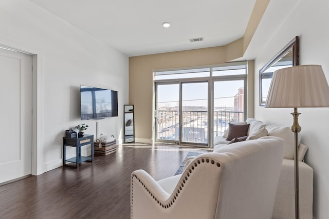 living room featuring dark wood-style floors, visible vents, and baseboards