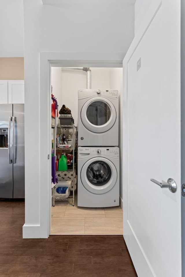 laundry room with laundry area, wood finished floors, and stacked washer / drying machine