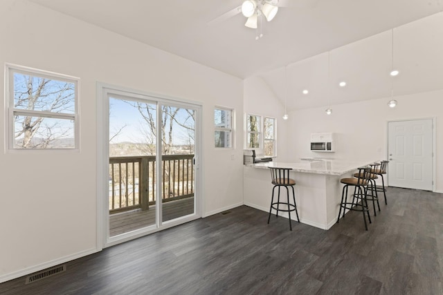 kitchen featuring a kitchen breakfast bar, lofted ceiling, visible vents, and dark wood-style floors