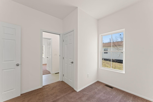 unfurnished bedroom with visible vents, multiple windows, baseboards, and carpet