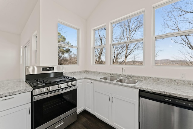 kitchen featuring a sink, stainless steel appliances, white cabinets, and vaulted ceiling