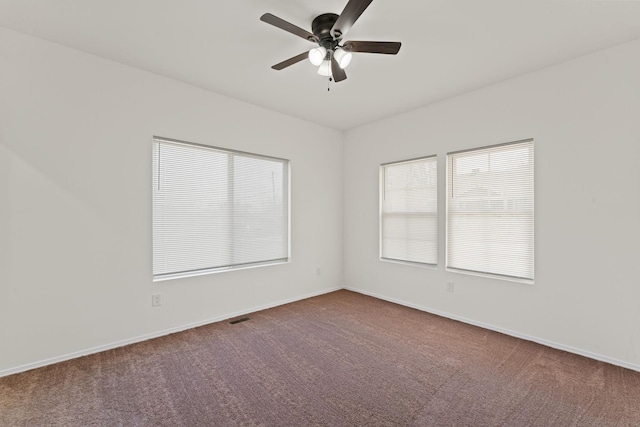 carpeted empty room with a ceiling fan, visible vents, and baseboards