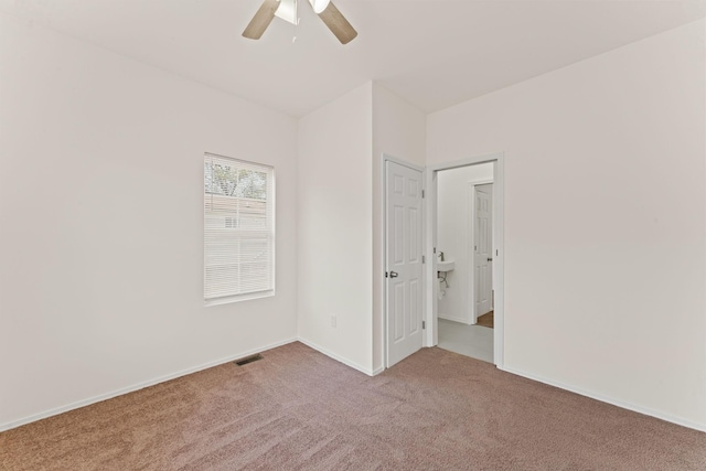 empty room with baseboards, visible vents, a ceiling fan, and carpet