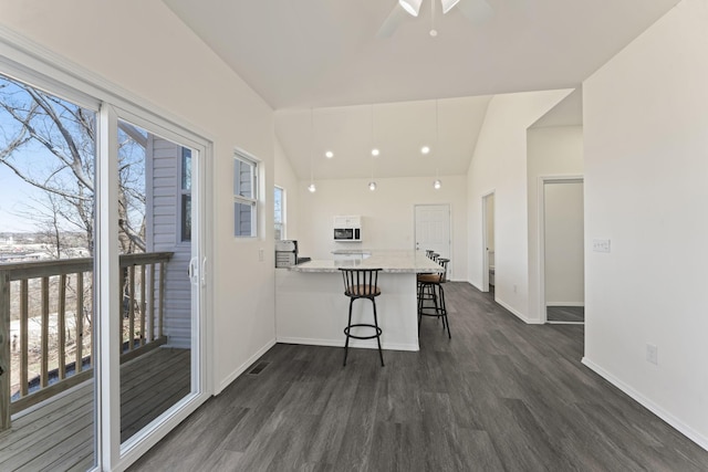 kitchen featuring a healthy amount of sunlight, a breakfast bar, lofted ceiling, and dark wood-style flooring