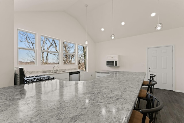 kitchen with a kitchen bar, dark wood-type flooring, a sink, stainless steel dishwasher, and white microwave