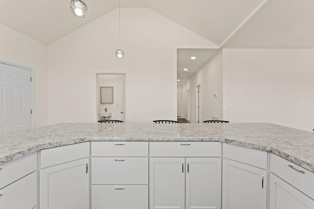 kitchen with vaulted ceiling, white cabinets, and light countertops