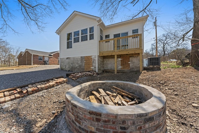 back of property with central air condition unit, a fire pit, and a wooden deck