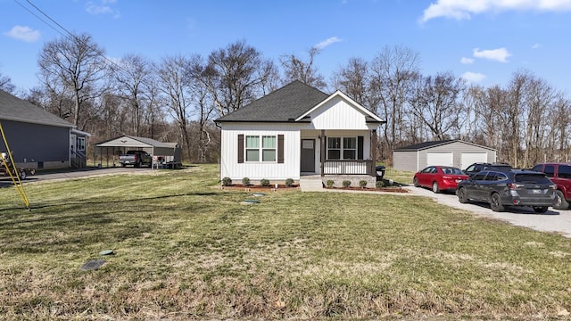 view of front of property featuring a front lawn, a detached garage, covered porch, an outdoor structure, and a shingled roof