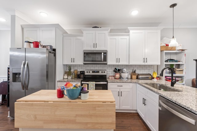 kitchen with tasteful backsplash, stainless steel appliances, white cabinetry, wood counters, and a sink