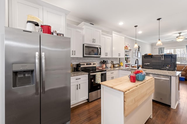 kitchen featuring dark wood finished floors, decorative backsplash, appliances with stainless steel finishes, a peninsula, and a sink