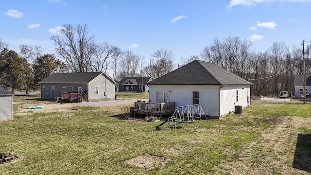 rear view of property featuring a yard, roof with shingles, central AC, and a deck