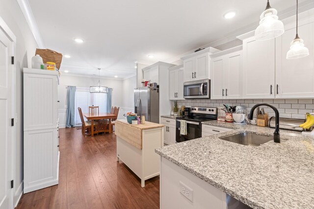 kitchen featuring a kitchen island, dark wood finished floors, a sink, appliances with stainless steel finishes, and white cabinetry