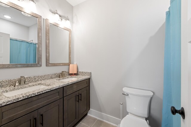 bathroom featuring a sink, baseboards, toilet, and tile patterned flooring