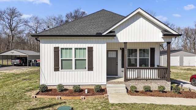 view of front of property with board and batten siding, a front yard, covered porch, and roof with shingles