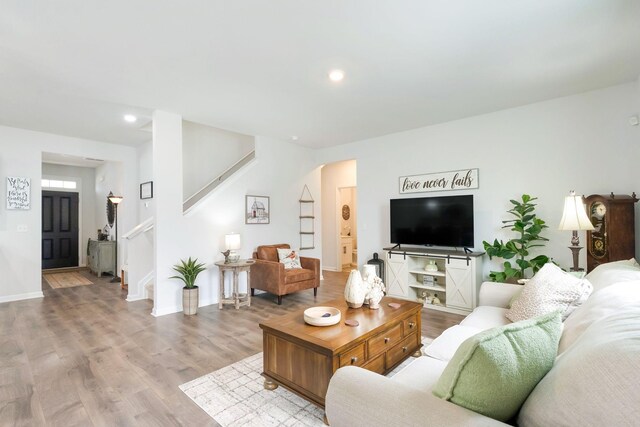 living room with stairs, baseboards, and wood finished floors