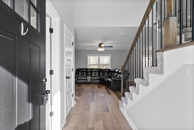 entryway featuring wood finished floors, ceiling fan, and stairway