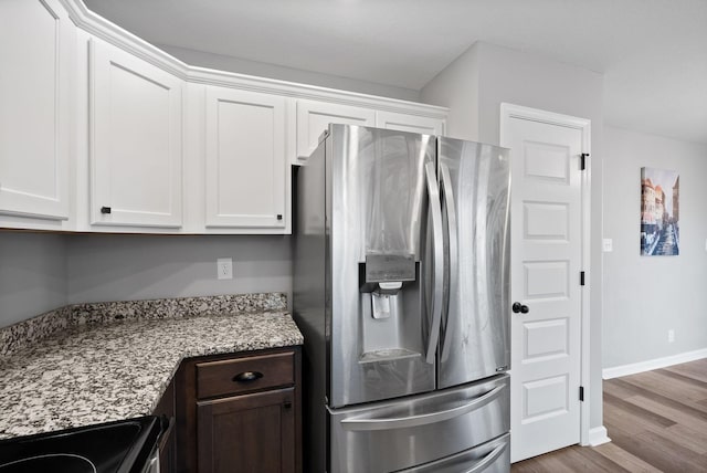 kitchen featuring electric stove, wood finished floors, stainless steel refrigerator with ice dispenser, and white cabinets