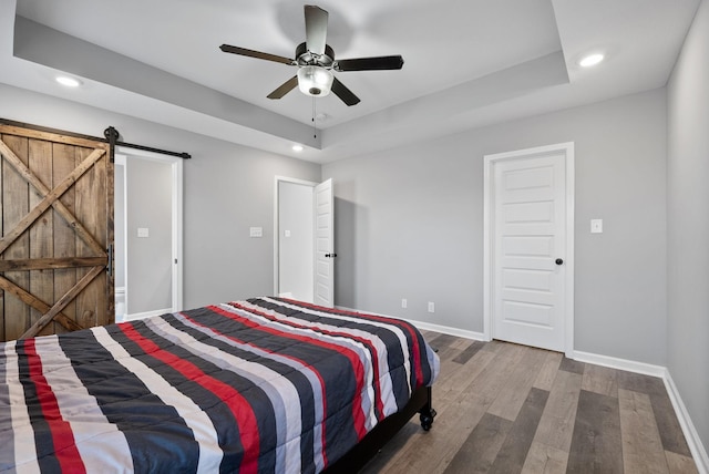 bedroom featuring a tray ceiling, baseboards, and wood finished floors